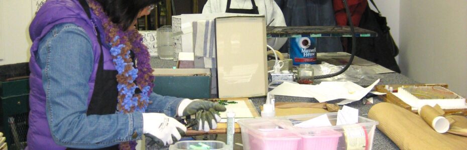 Two people working with materials on a table in a workshop.