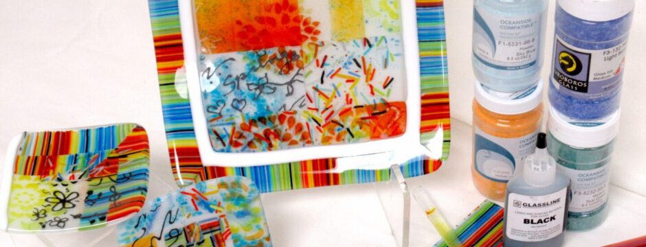 Colorful, hand-painted ceramic plates and art supplies on a white table.