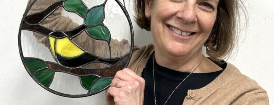 Woman holding stained glass art piece.