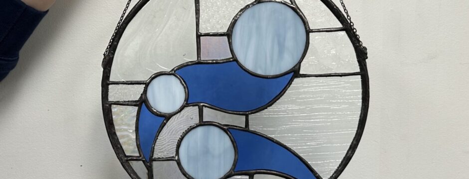 Round stained glass with abstract blue design.