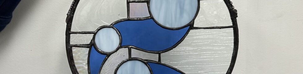 Round stained glass with abstract blue design.