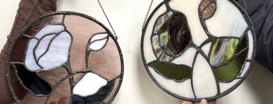 Two hands holding stained glass art.