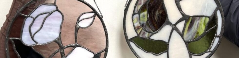 Two hands holding stained glass art.